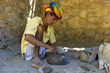 Indian potter in traditional Rajasthani turban works at home preparing clay in village of Nimaj, Rajasthan, Northern India