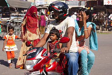 Indian family riding motorcycle, street scene at Sardar Market at Girdikot, Jodhpur, Rajasthan, Northern India