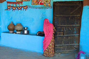 Hindu woman in traditional blue painted home in Hindu Brahman high caste village of Dhudaly  in Rajasthan, Northern India