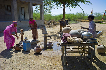 Indian women in sari fetching water pot from well at Jawali village in Rajasthan, Northern India