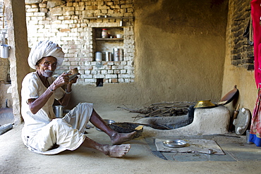 Indian man drinking buttermilk at home in Narlai village in Rajasthan, Northern India