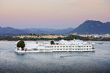 The Lake Palace Hotel, Jag Niwas, on island site on Lake Pichola in early morning with tourist boat leaving, Udaipur, Rajasthan, India