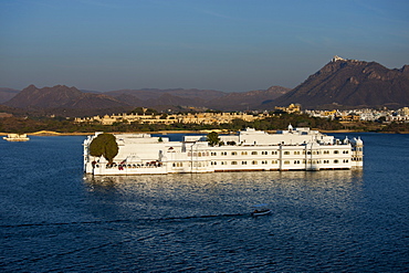 The Lake Palace Hotel, Jag Niwas, on island site on Lake Pichola in early morning with tourist boat leaving, Udaipur, Rajasthan, India