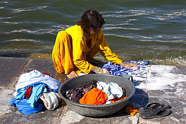 Young Indian girl squatting down to do her laundry in the waters of Lake Pichola, Udaipur, Rajasthan, Western India