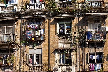 Tenement block traditional chawl housing scheme with air conditioning units and man in window in Parel area of Mumbai, India