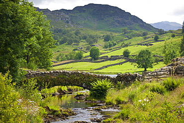 Packhorse Bridge across mountain stream at Watendlath in the Lake District National Park, Cumbria, UK