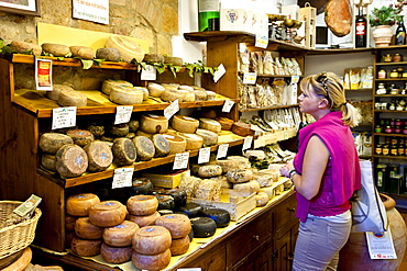 Shopper in Italian artisan cheese shop, Del Bottega Naturista selling Pecorino Stagionato aged cheese in Pienza, Tuscany, Italy