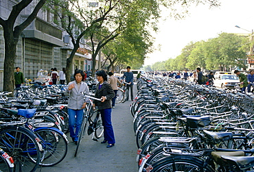 Young women parking bicycle in crowded bicycle park, Beijing, China