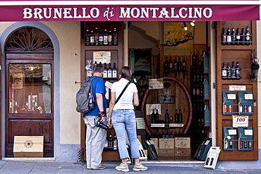 Couple shopping at Brunello Di Montalcino wine shop in ancient hill town of Montalcino in Val D'Orcia, Tuscany, Italy