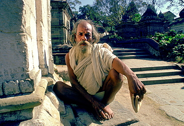 A holy man crouching at the Pashupatinath Temple on the Bagmati River in Nepal.  It is one of the holiest Hindu Temples in the world.