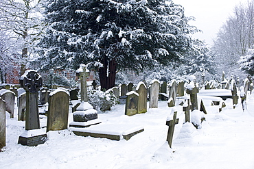 Snow-covered gravestones in Hampstead Parish Graveyard in Church Row and Holly Place in Hampstead, North London, UK