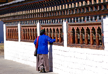 Bhutanese woman touching prayer bells while praying at the Tashichho Dzong in Bhutan