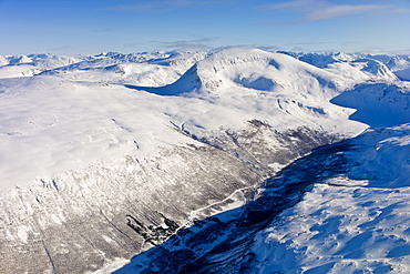 Aerial view of arctic landscape, snow covered road and Lyngen Alps from aircraft approaching Tromso in the Arctic Circle in Northern Norway