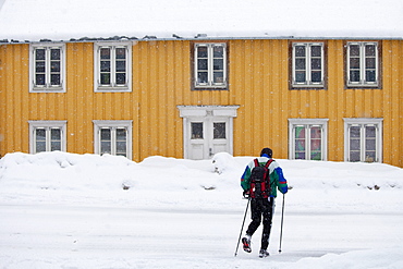 Man with walking poles passes traditional wooden buildings on Storgata in the quaint area of Tromso, Arctic Circle, Northern Norway