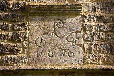 Date 1676 of traditional 17th Century cottage of old Cotswold stone at Taynton in The Cotswolds, Gloucestershire, UK