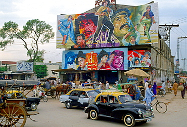 Street scene in Islamabad, Pakistan showing rickshaws, an old two-tone Morris Minor car and the local cinema advertising films often described as "Bollywood'.