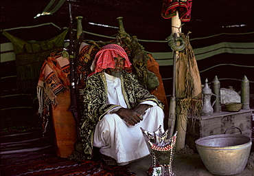 A Bedouin man in his Bedouin tent in the desert at Riyadh in Saudi Arabia. In front is an incense burner.