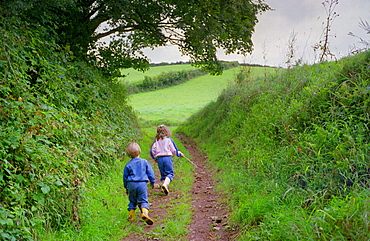 A five year oldgirl and four year old boy walking together in Devon