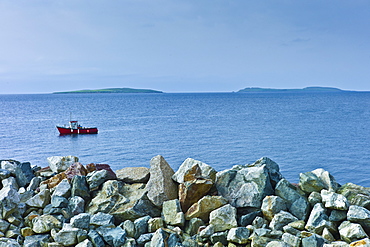 Fishing boat with Saltee Islands in background and sea defences, Kilmore, County Wexford, Southern Ireland