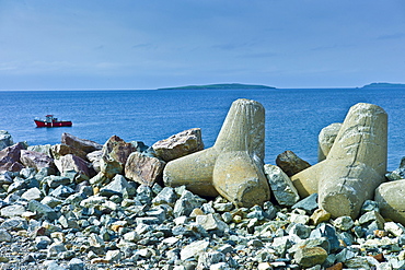 Fishing boat with Saltee Islands in background and sea defences, Kilmore, County Wexford, Ireland