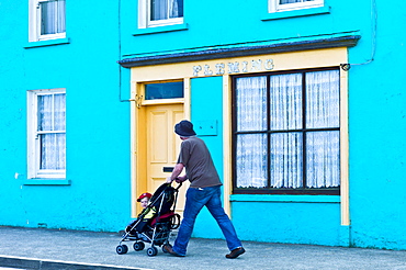 Man wheels child in stroller along the street in Courtmacsherry, County Cork, Ireland