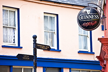 Signpost to Garda, Churches and Cemetery next to Guinness advertisement at bar in Timoleague, West Cork, Ireland