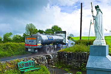 Milk tanker lorry passes religious shrine of Irish patron saint St Patrick in Ballingarry, County Limerick, Ireland