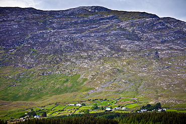 Homes nestling at the foot of the Maumturk mountain range near Recess in Connemara, County Galway, Ireland