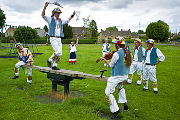 Morris dancers, Icknield Way Morris Men, in children's playground at The Kings Head Pub, Bledington, Oxfordshire, UK