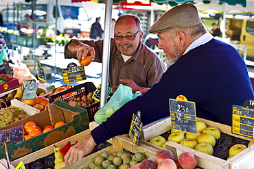 Frenchmen working  on fruit staff at food market at Esplanade  des Quais in La Reole, Bordeaux region, France