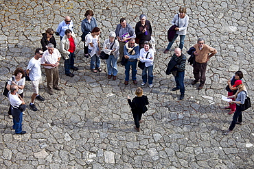 Tourists listen to tour guide in quaint street in St Emilion, Bordeaux, France