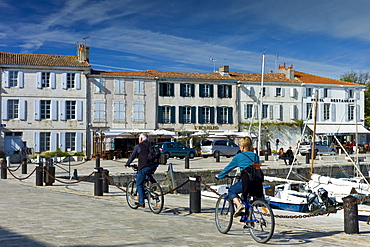 Tourists cycling along the harbour at Quai de Senac in La Flotte, Ile de Re, France