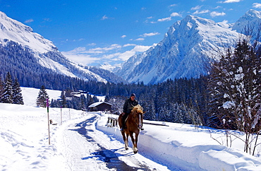 Man riding his home home at Klosters - Amongst the Silvretta group of the Swiss Alps. Road to Silvretta.Mountain at right is P.Linard 3411 metres high