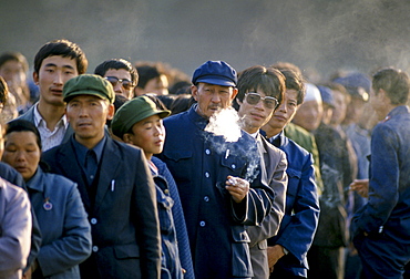 Chinese people, some smoking cigarettes, in Tiananmen Square in Peking, now Beijing, China in the 1980s