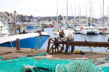 Welder at work at boatyard at Channel port of St Vaast La Hougue in Normandy, France