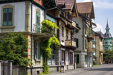 Jogger passes traditional houses in Neugasse at Interlaken in the Bernese Oberland, Switzerland, Europe