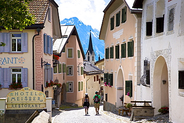 Tourists pass Hotel Meisser in Engadine Valley village of Guarda, renowned for its painted stone 17th century buildings, Graubunden, Switzerland, Europe