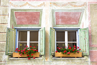 Windows in old painted stone 17th century building in the Engadine Valley in the village of Guarda, Graubunden, Switzerland, Europe