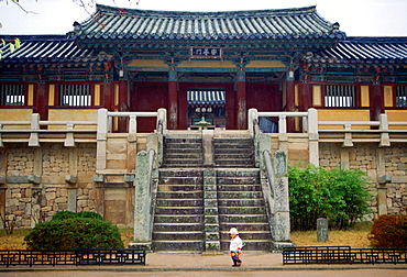 A small child in a sunhat strolling in front of the imposing Pulguksa Temple in South Korea