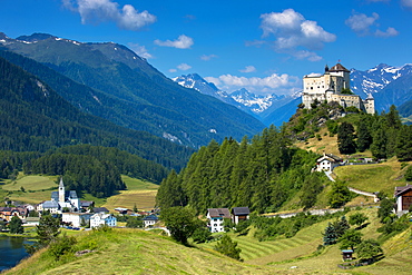 Tarasp Castle and Fontana village surrounded by larch forest in the Lower Engadine Valley, Switzerland, Europe