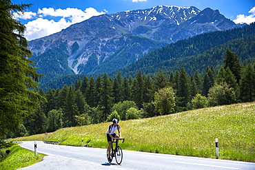 Cycling uphill in the Swiss National Park with background of the Swiss Alps, Switzerland, Europe