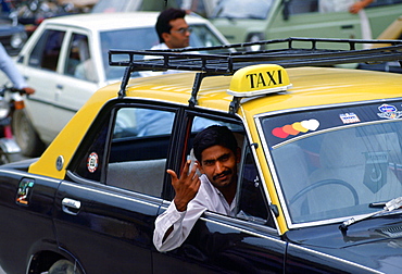 Taxi driver in Islamabad, Pakistan gesturing with his hand as he leans out of his car window.