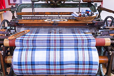 Highland tartan fabric on traditional weaving loom at Lochcarron Weavers in Lochcarron in the Highlands of Scotland, United Kingdom, Europe