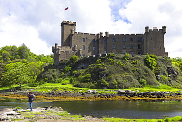 Tourist taking photographs at Highland fortress Dunvegan Castle, the ancestral home of the MacLeod clan, and loch on the Isle of Skye, Inner Hebrides, Scotland, United Kingdom, Europe