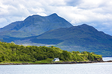 Solitary whitewashed croft cottage across the Sound of Sleat with Knoydart mountain behind, Isle of Skye, Inner Hebrides and Western Isles, Scotland, United Kingdom, Europe