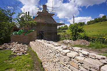 Home improvement, cottage renovation and newly built dry stone wall constructed of new Cotswold stone by traditional methods at period property, Swinbrook, Oxfordshire, Cotswolds, England, United Kingdom, Europe