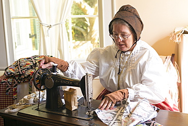 Craftsperson with sewing machine at Vermilionville history museum of Acadian, Creole, Native American cultures, Louisiana, USA