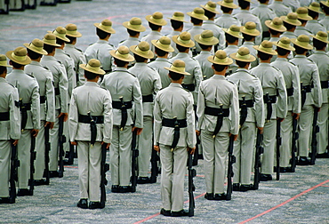 Ranks of Gurkha soldiers standing in lines with their traditional Kukri knives attached to scabbards on their belts and their rifles at their sides, Hong Kong