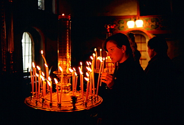 Woman worshipper holding a lighted candle in a church in Zagorsk, Russia