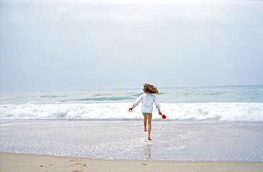 An eight year old girl running into the sea in France